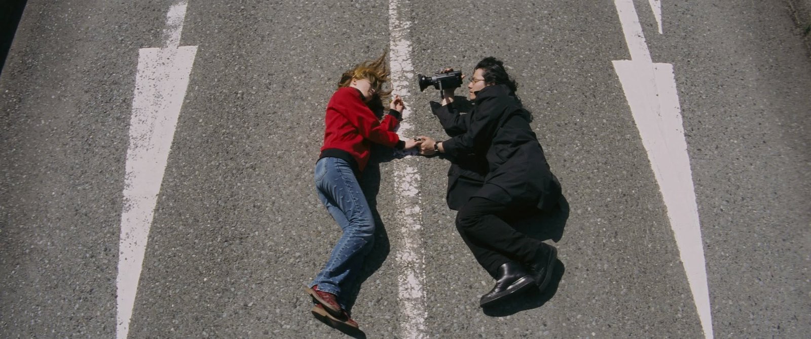 An image of Ritual/Shiki-jitsu (2000). Depicting the main character looking at the heroine through a camera.