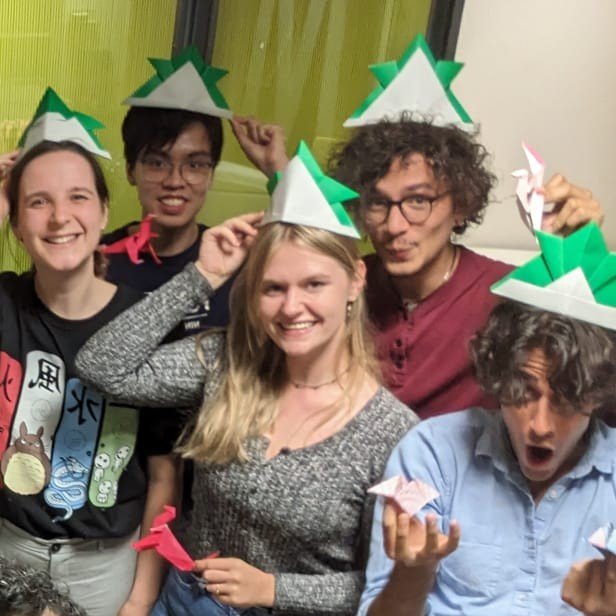 Kinjin members posing with their origami hats